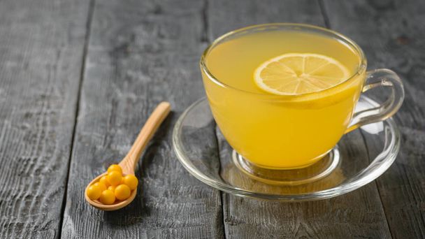Compresse gialle in un cucchiaio di legno e una bevanda di zenzero e agrumi su un tavolo nero
. - Foto, immagini