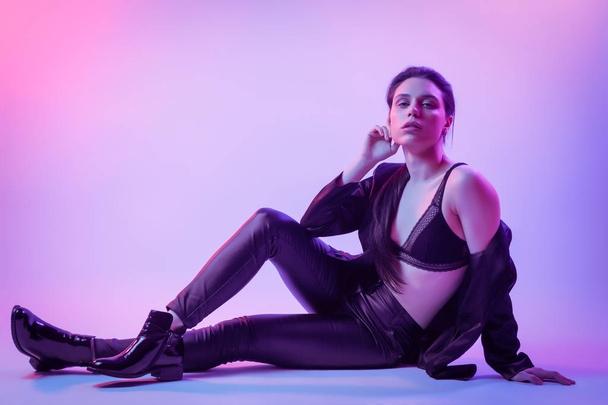 Warrior woman in Pink Blue neon light, Trendy fashionable Hairstyle. High Fashion. Cinematic night portrait of woman in jacket, pants and underwear  posing in  neon lights - Foto, Imagem