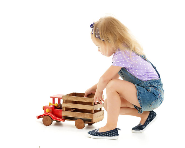 Little girl is playing with a wooden car. - Foto, Imagen
