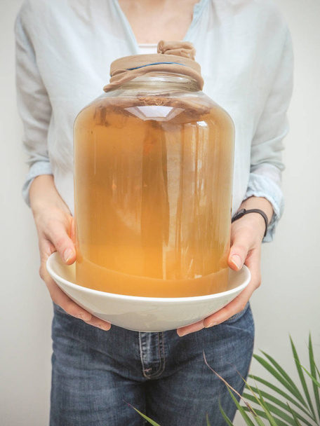 Caucasian woman holding a big jar with homemade kombucha tea - Photo, Image