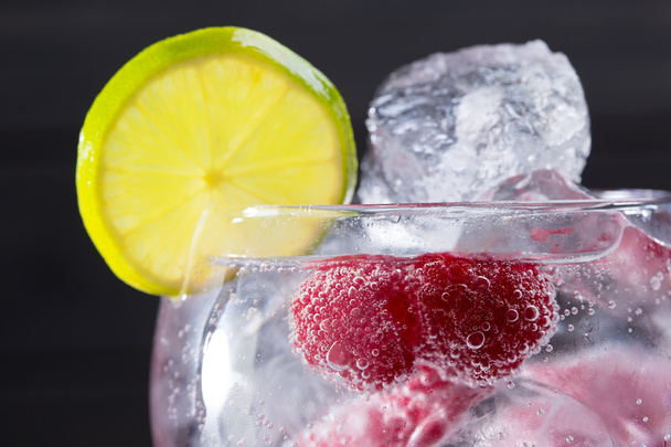 Gin tonic cocktail with raspberry and ice macro closeup - Фото, изображение