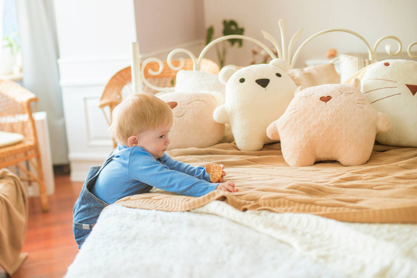 Little cute baby at home in the nursery plays with children's pillow toys - Photo, image
