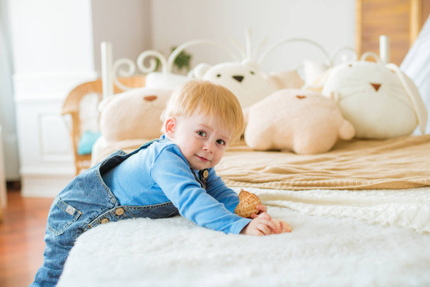 Little cute baby at home in the nursery plays with children's pillow toys - Foto, imagen