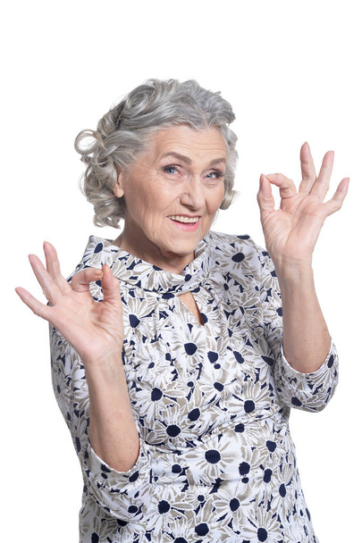 portrait of beautiful senior woman showing ok signs against white background - Foto, Bild
