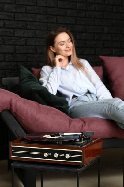 Mujer joven escuchando música a través de un viejo tocadiscos en casa
 - Foto, imagen