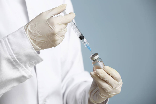 Cosmetologist holding syringe with filler and ampule on color background, closeup - Foto, Imagem