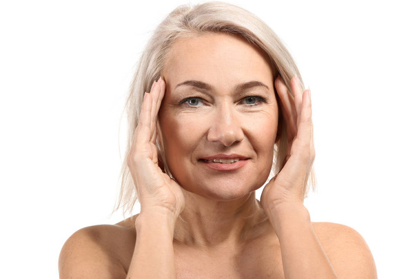 volwassen vrouw geven zichzelf gezicht massage op witte achtergrond - Foto, afbeelding