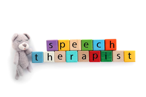 Cubes with text SPEECH THERAPIST and toy on white background - Photo, Image
