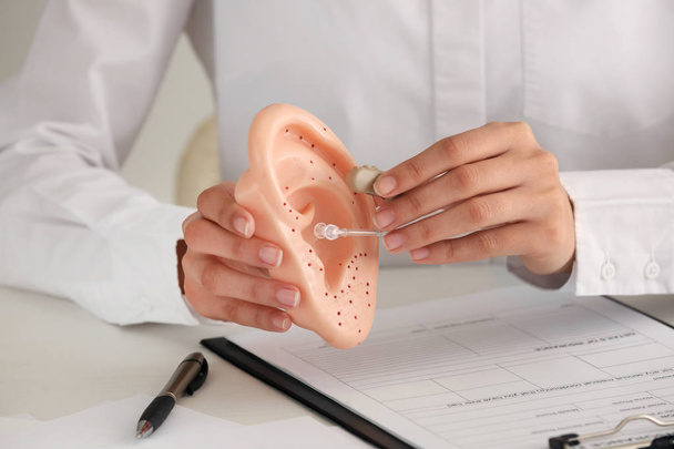 Female doctor with hearing aid and model of ear at table, closeup - Photo, Image