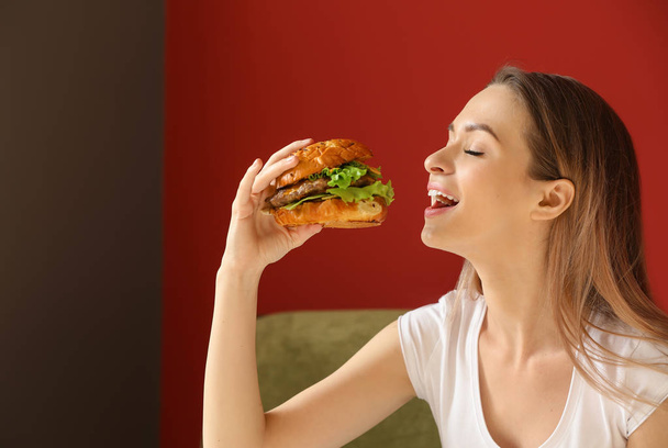 Belle jeune femme manger hamburger savoureux à l'intérieur
 - Photo, image