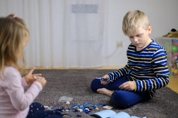 Δύο παιδιά που παίζουν με τα μέρη των πολύχρωμο μπλοκ πλαστική κατασκευή. - Φωτογραφία, εικόνα