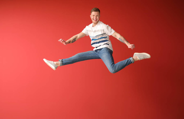 Handsome jumping man against color background - 写真・画像