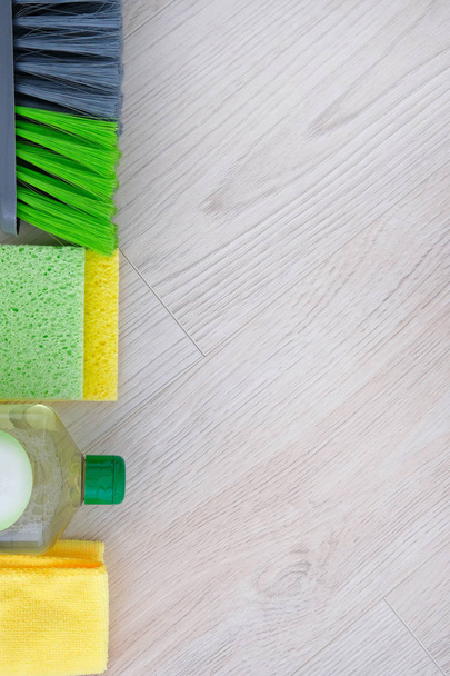 Set of green cleaning products on wooden background. Detergent in plastic bottle, sponges and brush. Service concept. Top view. Close up. - Photo, Image