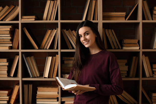 Портрет красивої молодої жінки з книгою в бібліотеці
 - Фото, зображення