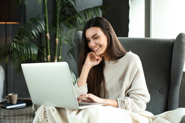 Beautiful young woman using laptop at home - Fotografie, Obrázek