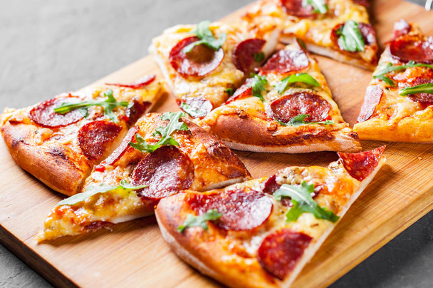 Pepperoni Pizza with Mozzarella cheese, salami, Tomato sauce, pepper, Spices and Fresh arugula. Italian pizza on Dark grey black slate background - Φωτογραφία, εικόνα