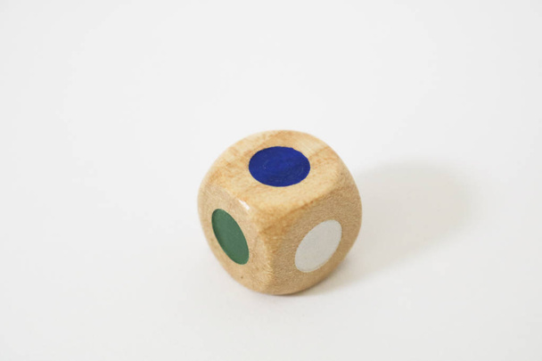 Close-up of a wooden dice with faces of different colors, on a white background, parlor games - Photo, Image
