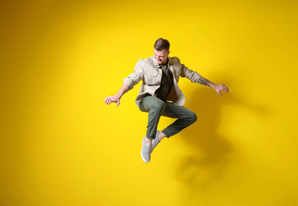 Handsome jumping man against color background - Foto, Imagen