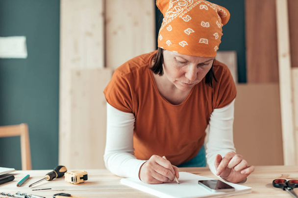Female carpenter doing financial calculation - Foto, Bild