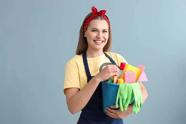 Portrait of beautiful woman with cleaning supplies on color background - Foto, immagini