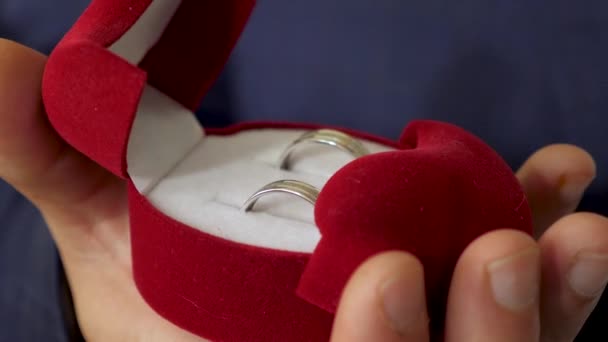 Bruidegom houdt doos met trouwringen in zijn hand voor voorstel aan zijn geliefd. Close-up. Maken van de nieuwe familie. - Video