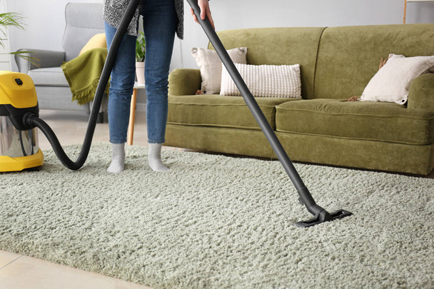 Frau putzt Teppich zu Hause mit Staubsauger - Foto, Bild