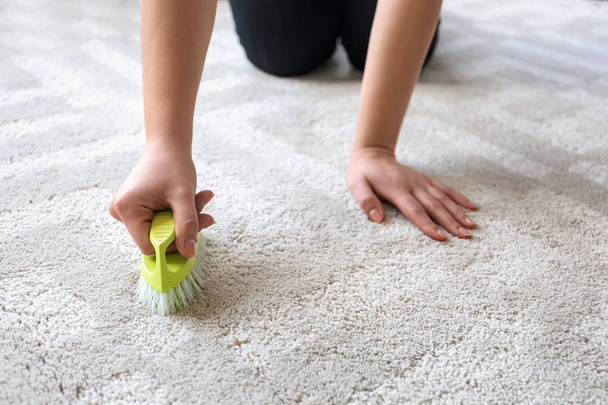 Жінка прибирає килим вдома
 - Фото, зображення