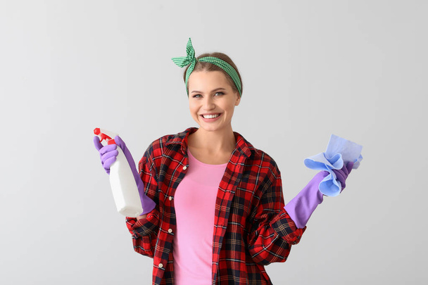 Portrait of beautiful woman with cleaning supplies on light background - Photo, Image