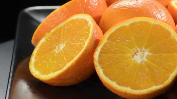 Sinaasappels in tweeën geknipt draaiend op een zwart dienblad - Video