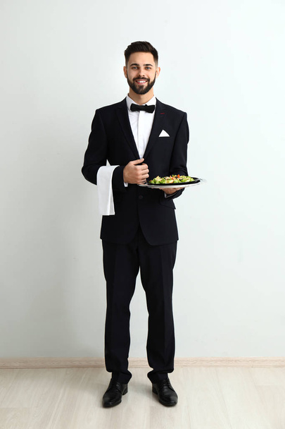 Waiter with fresh salad near light wall - Photo, Image