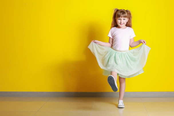 Porträt eines glücklichen kleinen Mädchens in der Nähe der Farbwand - Foto, Bild