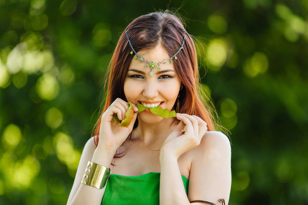 Beautiful young asian woman with a peel of fresh kiwi in teeth - Foto, Imagen