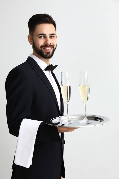 Ober met glazen champagne op lichte achtergrond - Foto, afbeelding