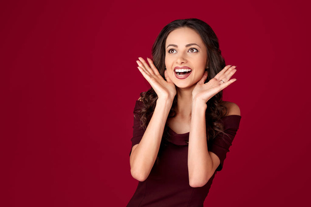 Photo of charming young woman in maroon dress over red background. - Foto, Imagem