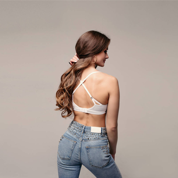 Brunette slim model in jeans and sports bra. - Фото, зображення