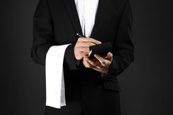 Όμορφος σερβιτόρος με notebook σε σκούρο φόντο - Φωτογραφία, εικόνα