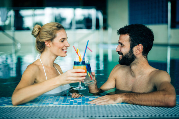 Happy attractive couple relaxing in swimming pool - 写真・画像