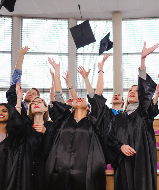 Groupe multi ethnique d'étudiants diplômés jetant des chapeaux
 - Photo, image