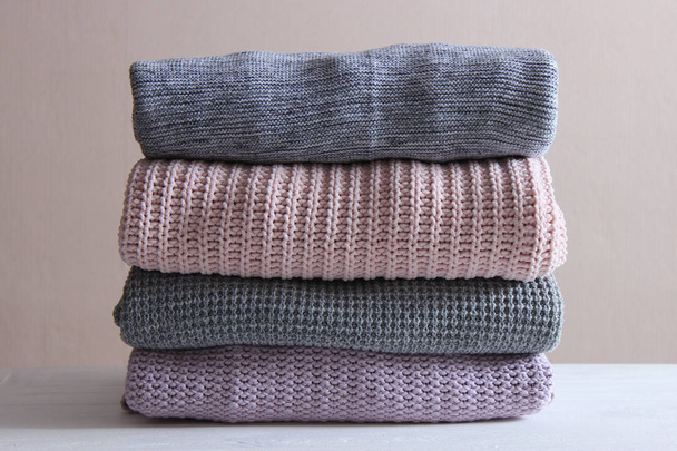 A pile of warm sweaters on a wooden table on a light background. Autumn and winter clothes. - Φωτογραφία, εικόνα