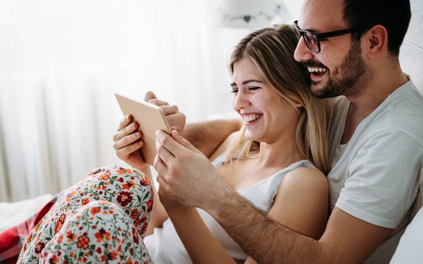Genç mutlu çift yatak odasında dijital tablet kullanma - Fotoğraf, Görsel