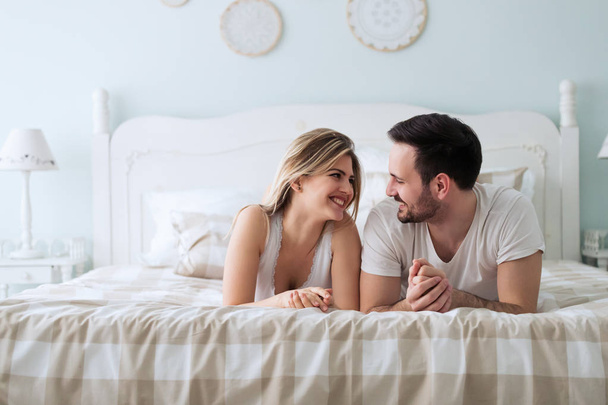Portrait of young attractive loving couple in bedroom - Fotografie, Obrázek