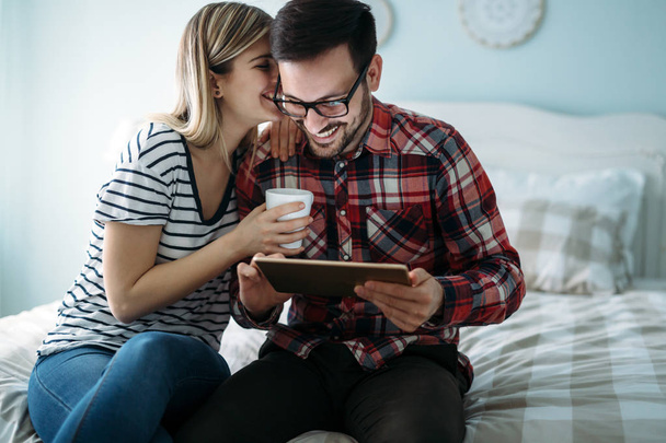 Mladý šťastný pár pomocí digitálních tabletu v ložnici - Fotografie, Obrázek