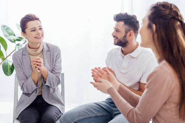 smiling women and man sitting and applauding during group therapy session - Photo, Image