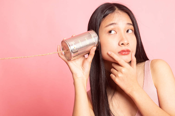 Young Asian woman hearing with tin can phone and thinking. - Foto, Imagem