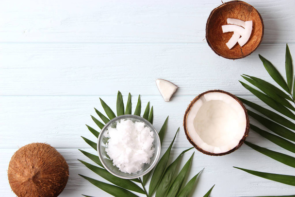 kokosové ořechy a kokosový olej s tropickými listy na dřevěném pozadí - Fotografie, Obrázek