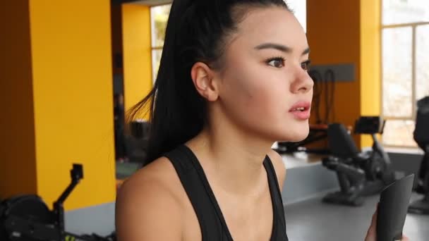 Genç Asyalı kız eliptik eğitmen spor salonunda spor yapıyor. - Video, Çekim