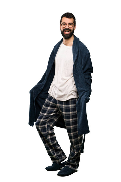 Man with beard in pajamas with glasses and smiling over isolated white background - Fotó, kép