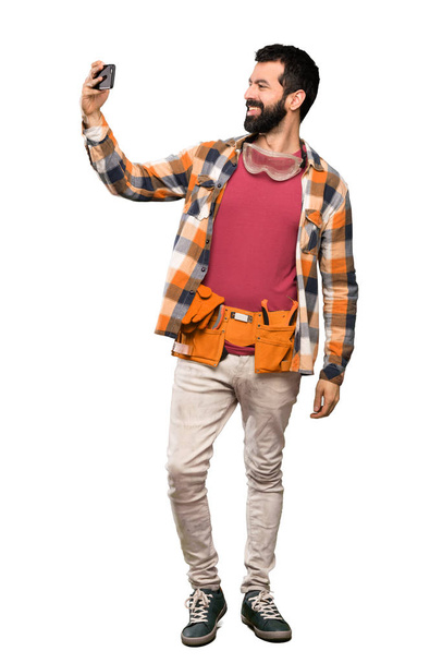 Craftsmen man making a selfie over isolated white background - Photo, Image