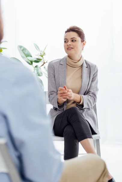 selective focus of woman in formal wear sitting and looking away during therapy session - Фото, изображение