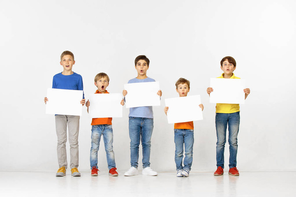 Group of children with a white banners isolated in white - Foto, Bild